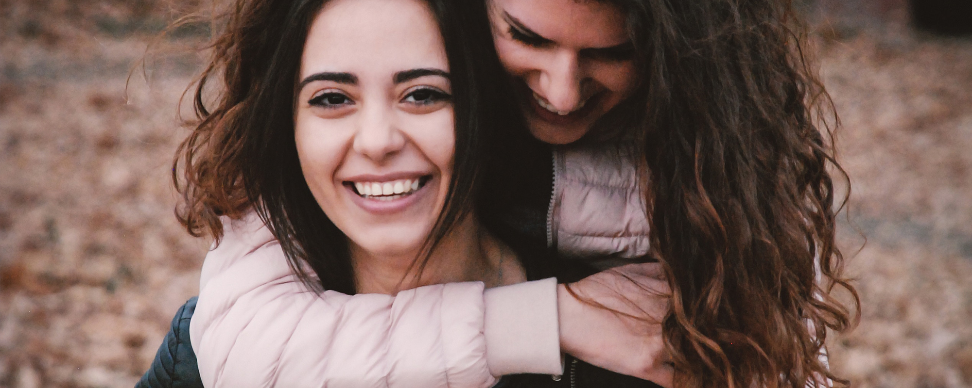 Imagen de dos amigas abrazándose y riéndose afuera - Saba